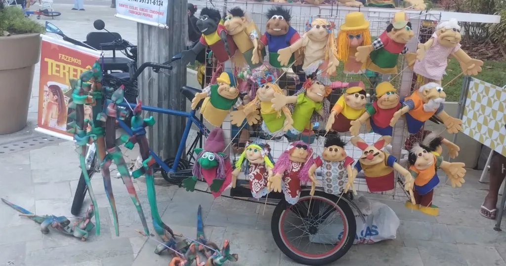 A Carrocela do Beto Fantoches: um triciclo cheio de fantoches coloridos, numa praça