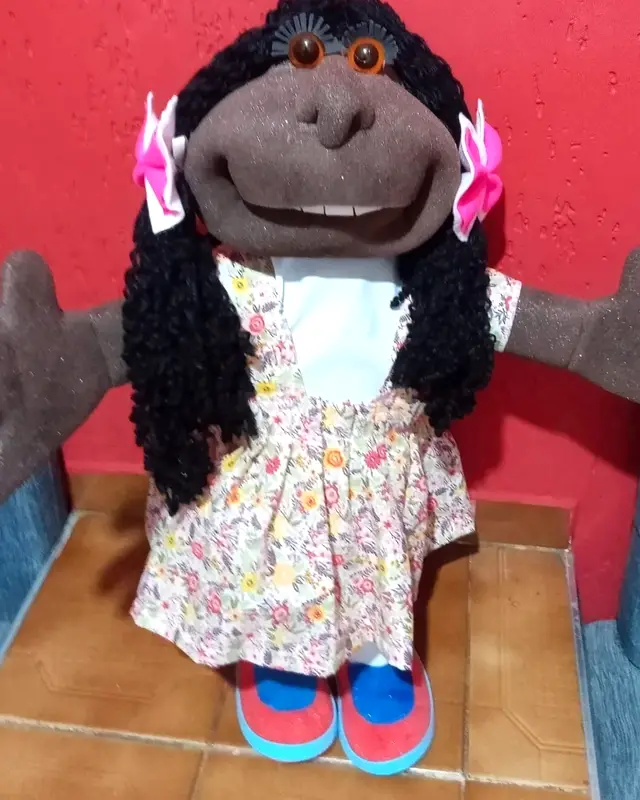 Boneca de tranças pretas com laços rosa e vestido florido