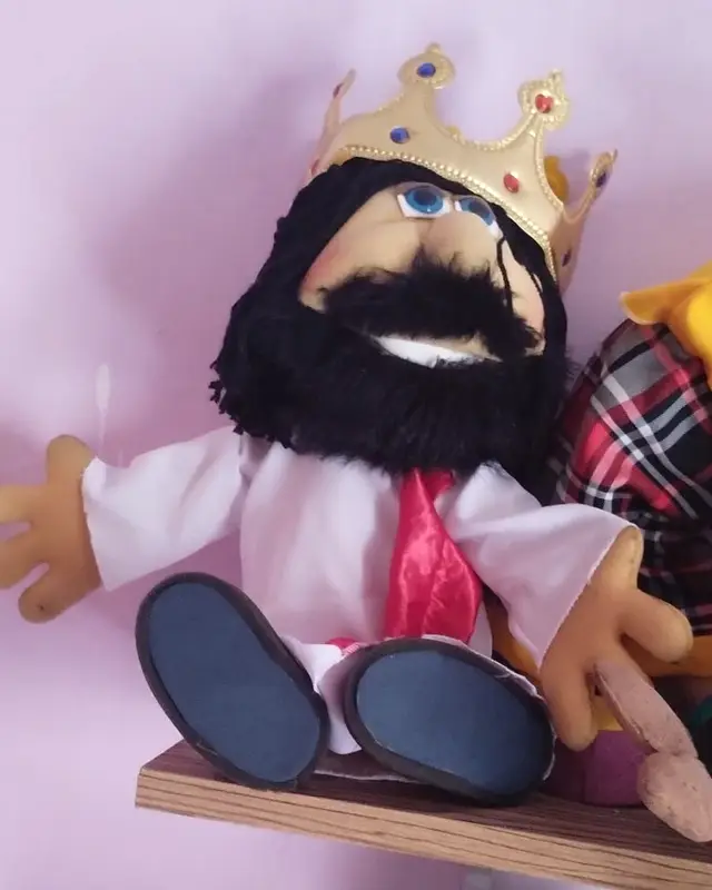 Rei, fantoche de barba preta e coroa dourada, sentado