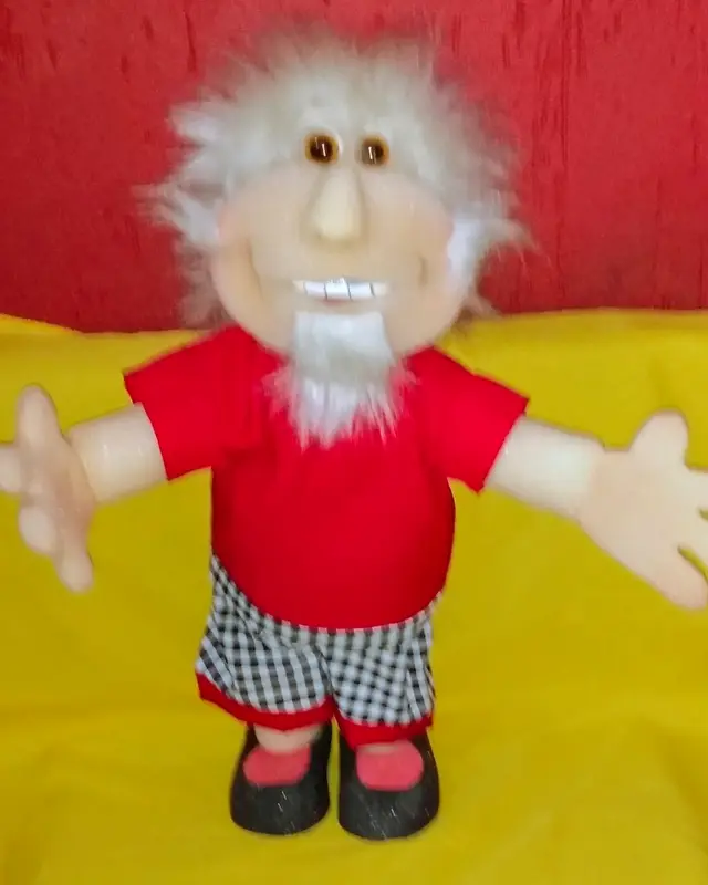 Vovô de cabelo e barba brancos, camisa vermelha e bermuda xadrez